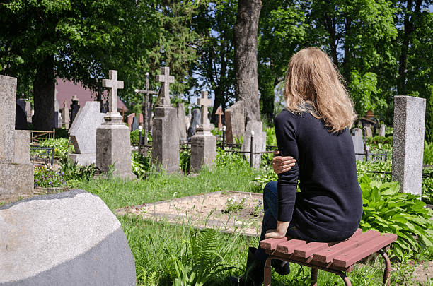 Woman sitting in a sunny cemetery.